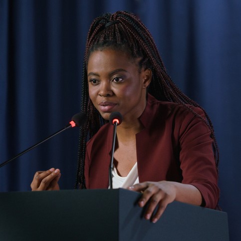 Young professional Black woman advocates at a microphone.